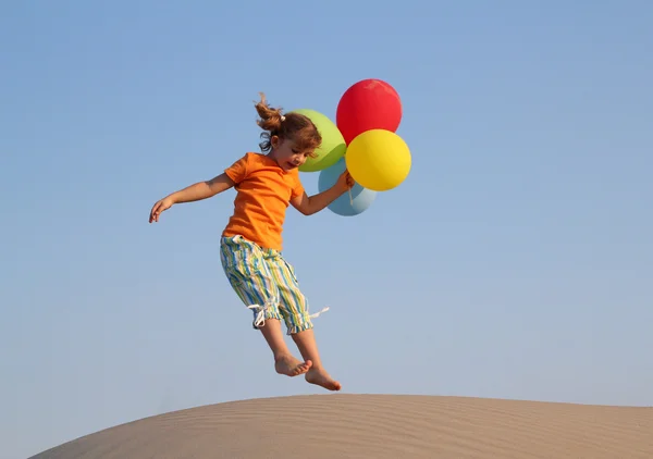 Glad liten flicka hoppa med ballonger — Stockfoto