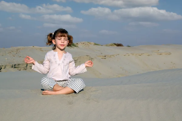 Little girl meditating in desert — Stockfoto