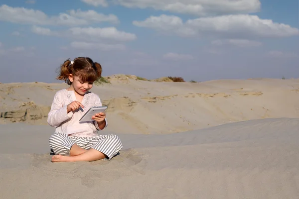 Happy little girl play with tablet pc in desert — Stock Photo, Image