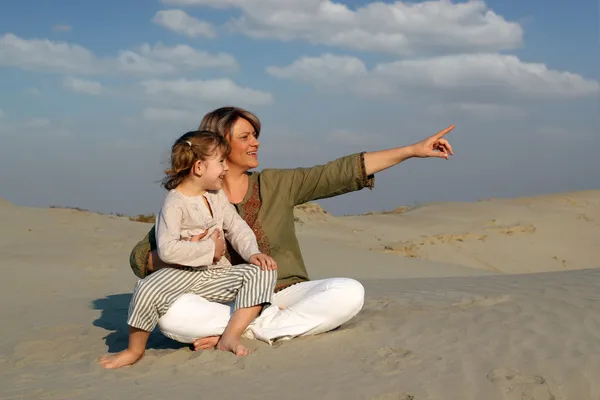 Happy mother and daughter sitting on sand family scene — Stock Photo, Image