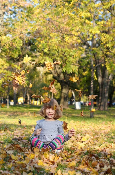 Fröhliche kleine Mädchen Spaß mit Herbstblättern — Stockfoto