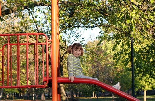 Kleines Mädchen sitzt auf Spielplatz-Rutsche — Stockfoto