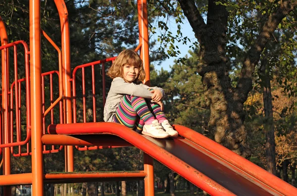 Little girl sitting on slide — Stock Photo, Image