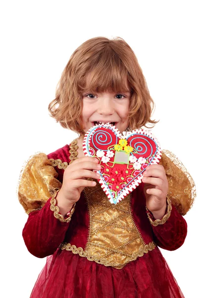 Little girl eating gingerbread heart — Stock Photo, Image