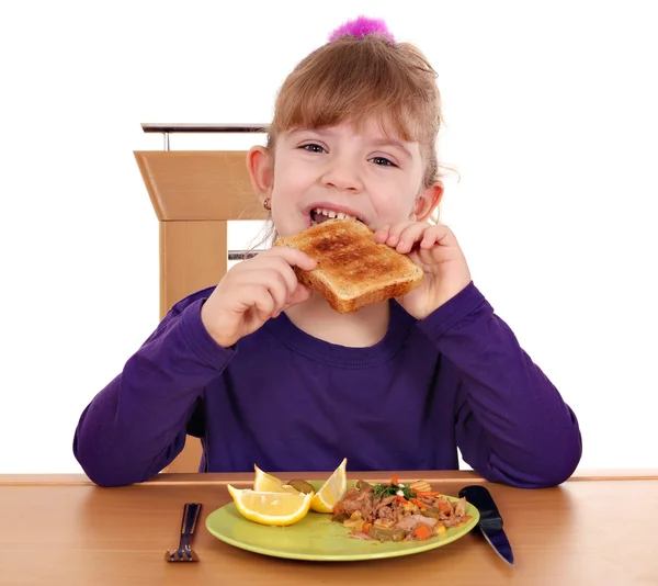 Hungry little girl eating bread — Stock Photo, Image