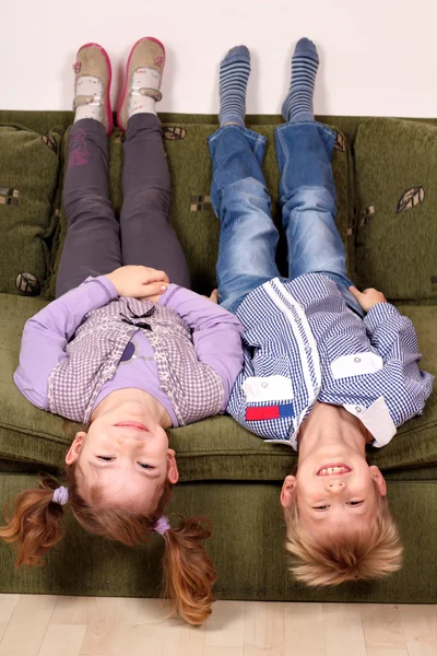 Menina e menino deitado de cabeça para baixo na cama — Fotografia de Stock