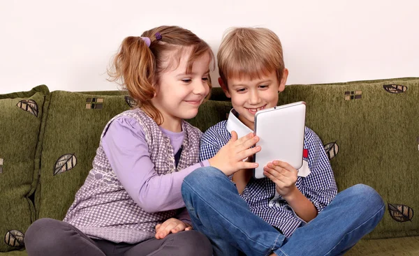 Gelukkig weinig meisje en jongen speelt met de tablet pc — Stockfoto