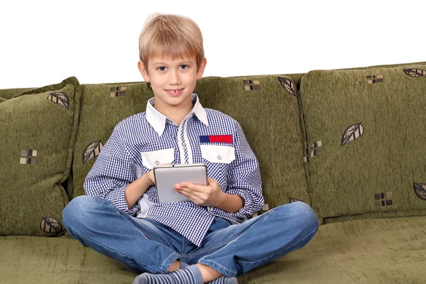 Lycklig pojke sitter på sängen och spela med TabletPC — Stockfoto