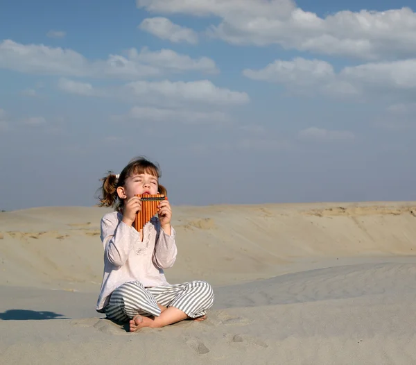 Menina jogar música no pan pipe no deserto — Fotografia de Stock