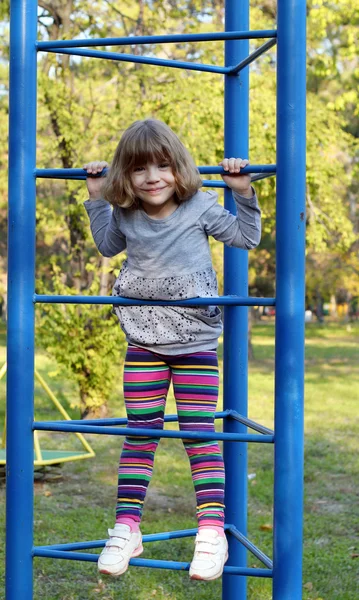 Szczęśliwa dziewczynka wspiąć się na plac zabaw w parku — Zdjęcie stockowe