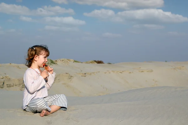 Kleines Mädchen sitzt auf Sand und spielt Musik — Stockfoto