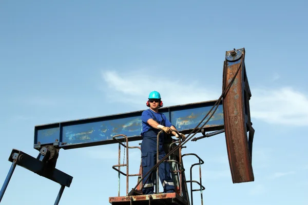 Olja då arbetstagaren med Solglasögon står vid pumpen jack — Stockfoto