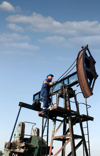 Olie werker klimt tot de pomp-aansluiting — Stockfoto