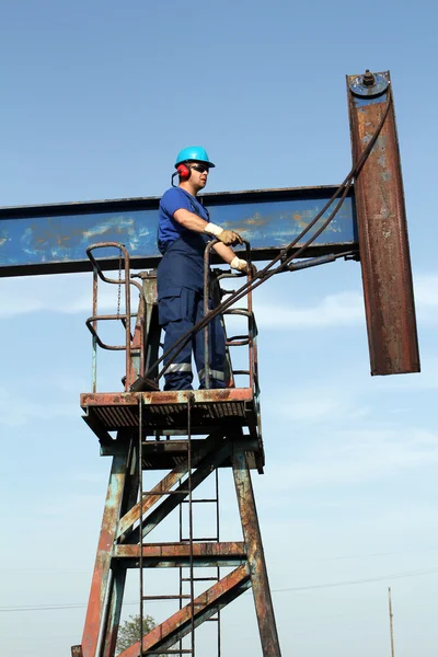 Operaio petrolifero in uniforme blu in piedi al cric pompa — Foto Stock