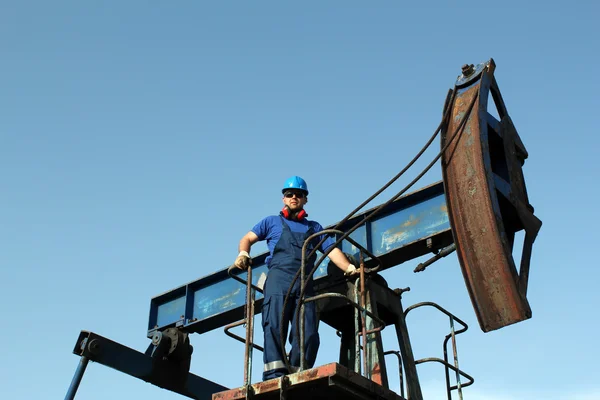 Ölarbeiter steht auf Pumpenheber — Stockfoto