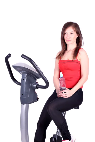 Fille avec bouteille d'eau assis sur cross trainer — Photo