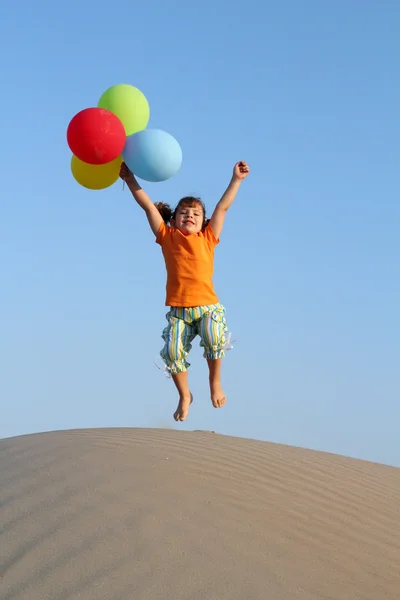Glad liten flicka hoppa på sanddyn — Stockfoto