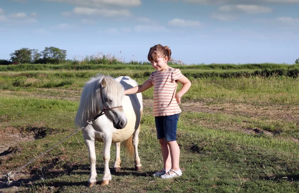 Petite fille et cheval de poney blanc sur pâturage — Photo