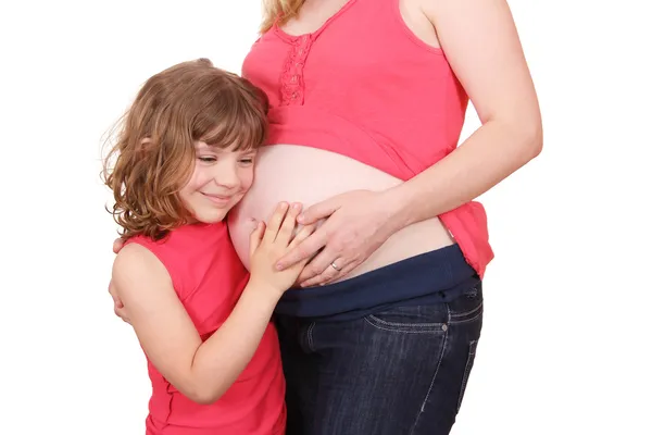 En liten flicka som omfamnar sin gravida mor — Stockfoto