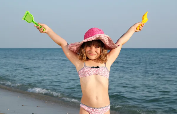 Glückliches kleines Mädchen mit den Händen nach oben am Strand — Stockfoto