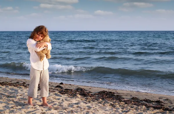 Beautiful little girl with teddy bear on beach — Stock Photo, Image