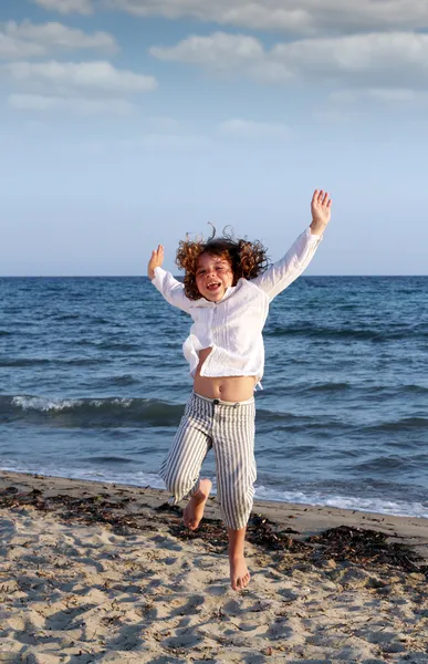 Happy little girl jumping on beach summer scene — Stock Photo, Image