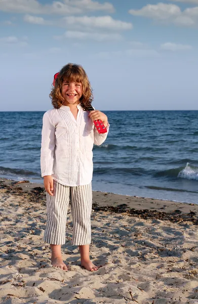 Glad vacker liten flicka med gitarr på stranden — Stockfoto