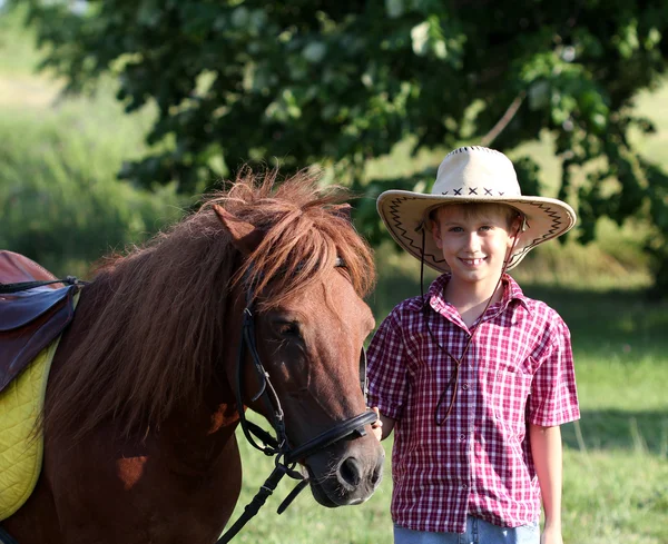 Menino com chapéu de cowboy e cavalo de pônei — Fotografia de Stock