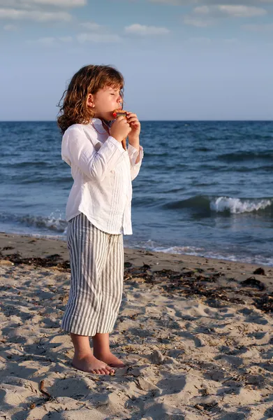 Schönes kleines Mädchen spielt Panflöte am Strand — Stockfoto