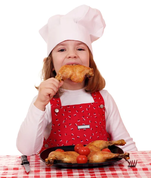 Hungry little girl cook eat chicken drumstick — Zdjęcie stockowe