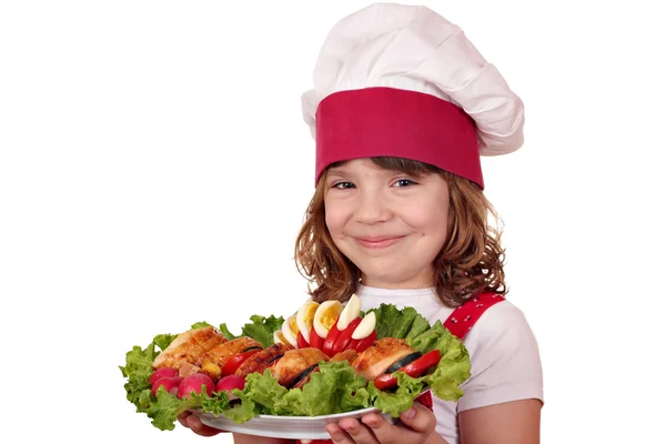 Beautiful little girl cook with roasted chicken meat and salad — Stock Photo, Image
