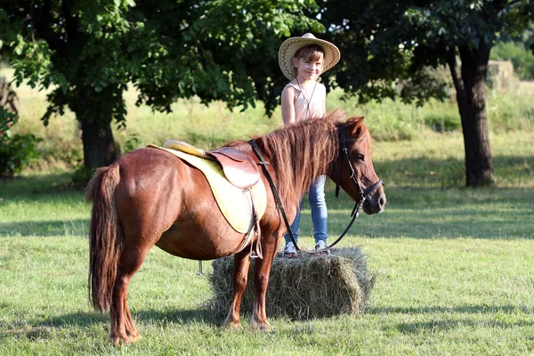 Κοριτσάκι με το καπέλο και το κατοικίδιο ζώο σας άλογο πόνυ — Φωτογραφία Αρχείου
