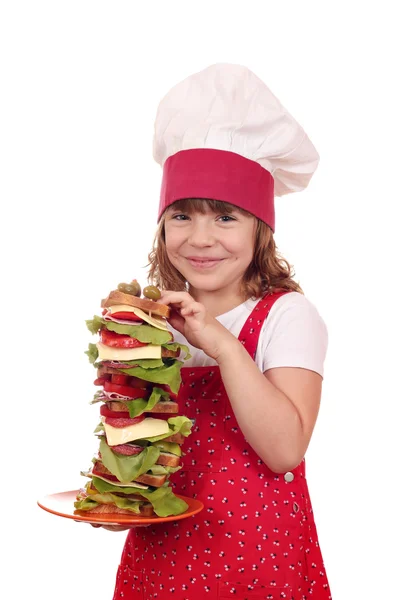 Menina feliz cozinheiro segurar sanduíche alto — Fotografia de Stock