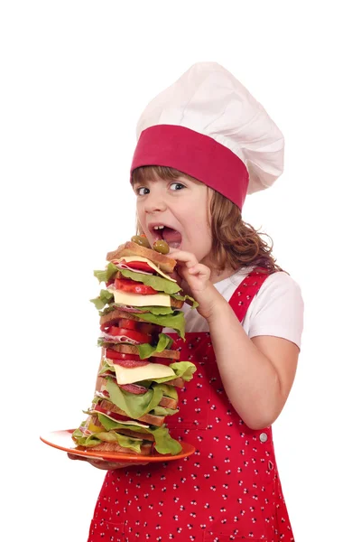 Hungry little girl cook eat large sandwich — Stock Photo, Image