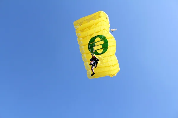 Parachutist met gele parachute op blauwe hemel — Stockfoto