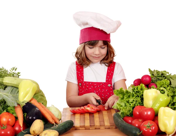 Pieni tyttö kokki leikattu tomaatit — kuvapankkivalokuva