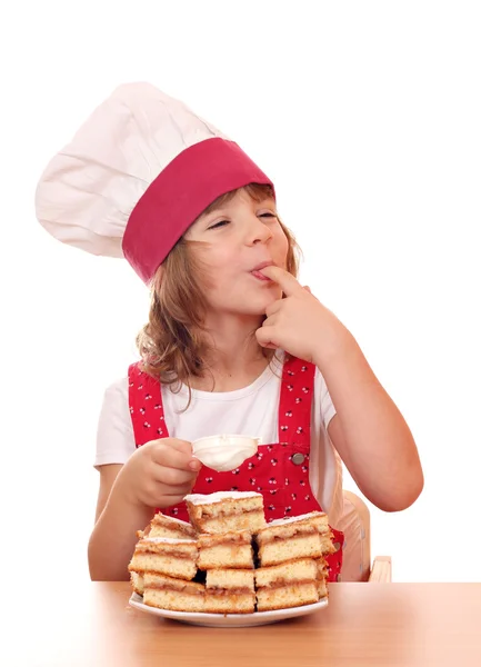 Little girl cook eat sugar from apple cake — Stock Photo, Image