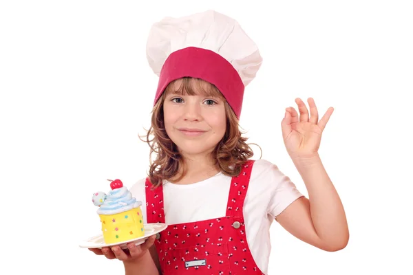 Küçük kız yemek cupcake ve ok el işareti ile — Stok fotoğraf