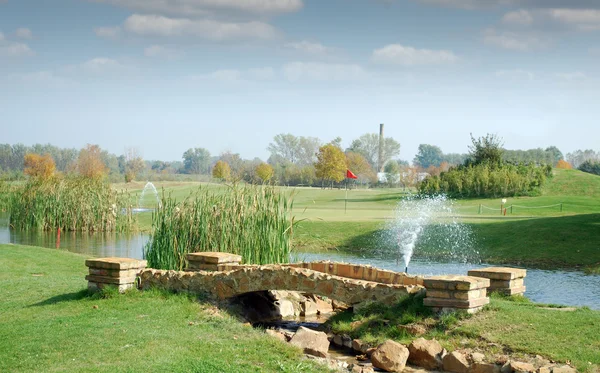 Поле для гольфа с маленьким каменным мостом — стоковое фото
