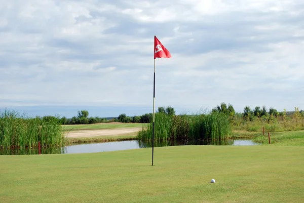 Campo de golfe com bandeira vermelha e bola — Fotografia de Stock