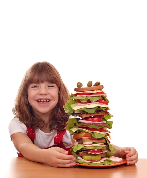 Happy little girl with tall sandwich on table — Stock Photo, Image