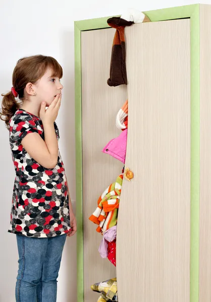 Shocked little girl looking into a messy closet — Stock Photo, Image