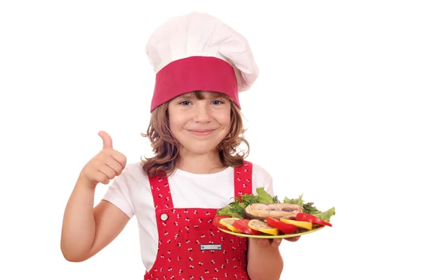 Petite fille cuisinier avec des fruits de mer de saumon et pouce levé — Photo