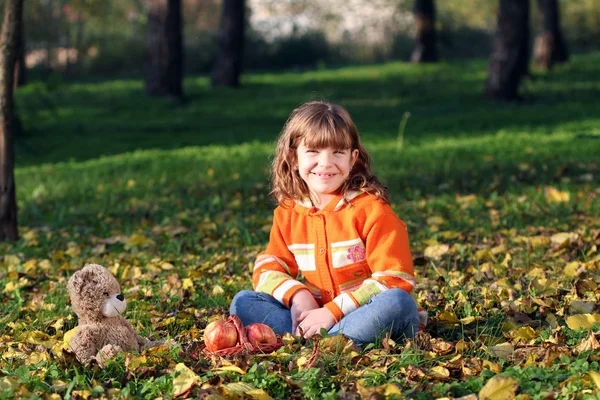 Heureuse petite fille assise dans le parc — Photo