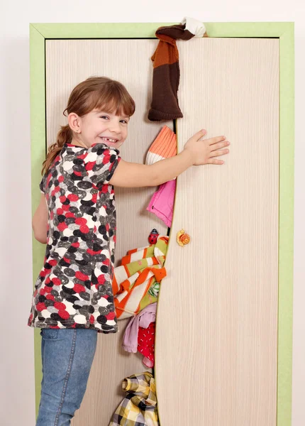 Kleines Mädchen versucht, unordentlichen Kleiderschrank zu schließen — Stockfoto