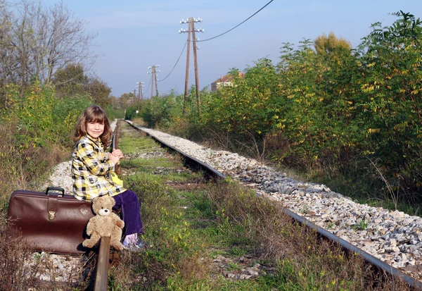 Bavul üzerinde oturan ve tren bekliyorsun küçük kız — Stok fotoğraf