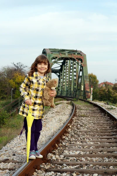 Красивая маленькая девочка, стоящая на железной дороге — стоковое фото