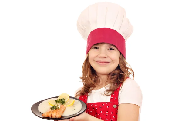 Gelukkig weinig meisje cook hold schotel met zalm zeevruchten — Stockfoto