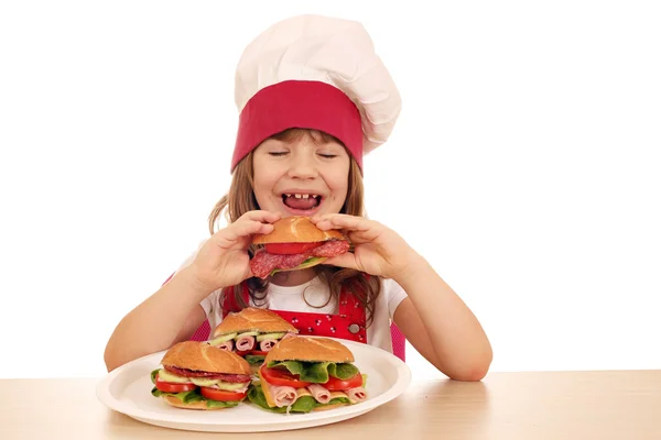 Hungrig liten flicka kock äter smörgås — Stockfoto