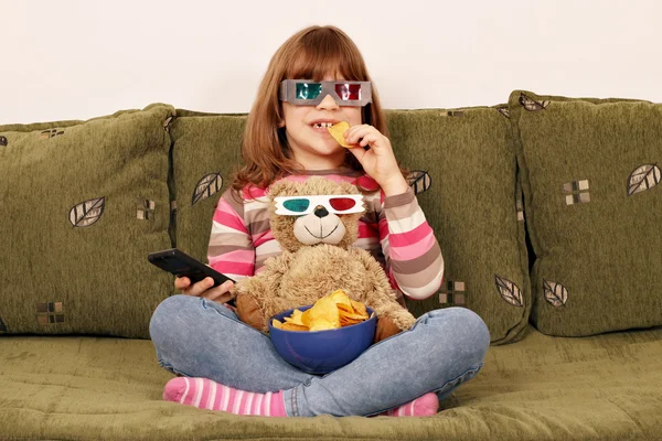 Little girl with 3d glasses eat chips and watching tv — Stock Photo, Image
